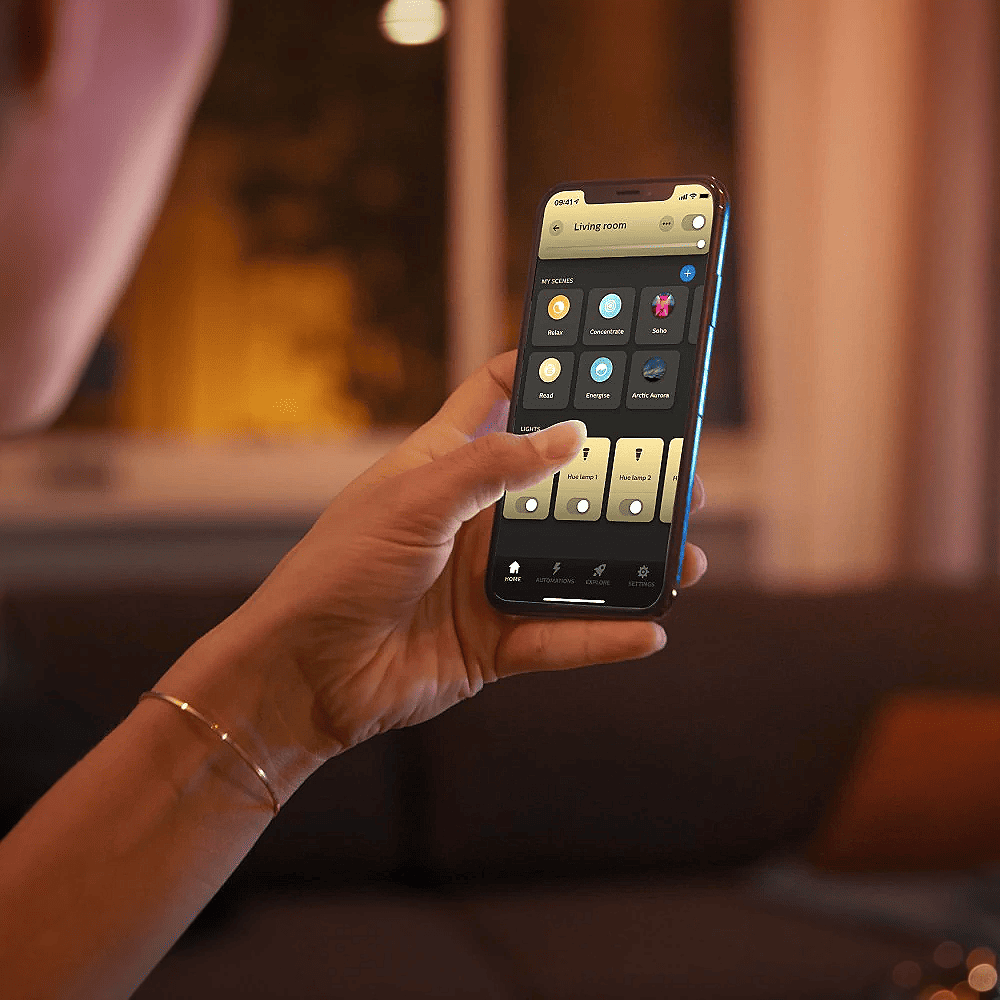 Philips Hue-appen på en mobiltelefon som viser skjermbildet for 'Living room' med ulike forhåndsinnstilte lysscener som 'Relax', 'Concentrate' og 'Arctic Aurora'.